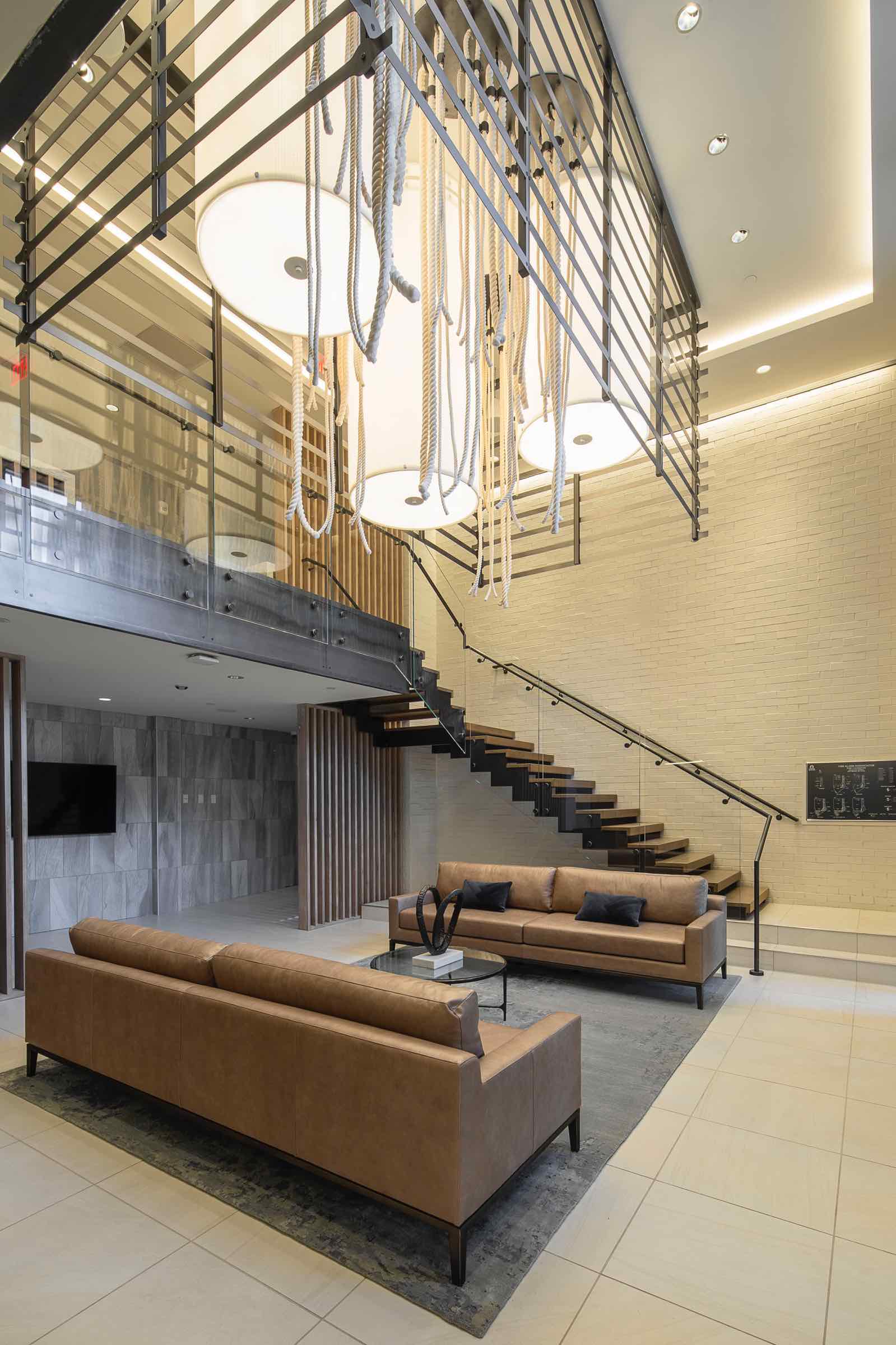 Lobby with a stylish staircase & comfy couches. One of the amenities of 250 Mission in Baltimore, MD.