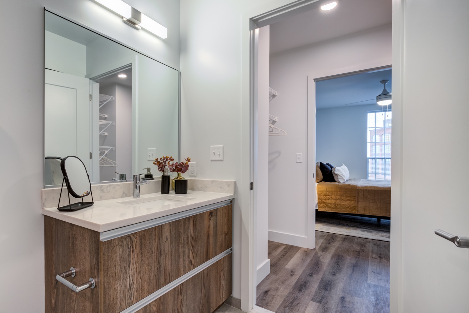 A bathroom with a sink and mirror. Bedroom in the background. Inside our luxury apartments at 250 Mission.