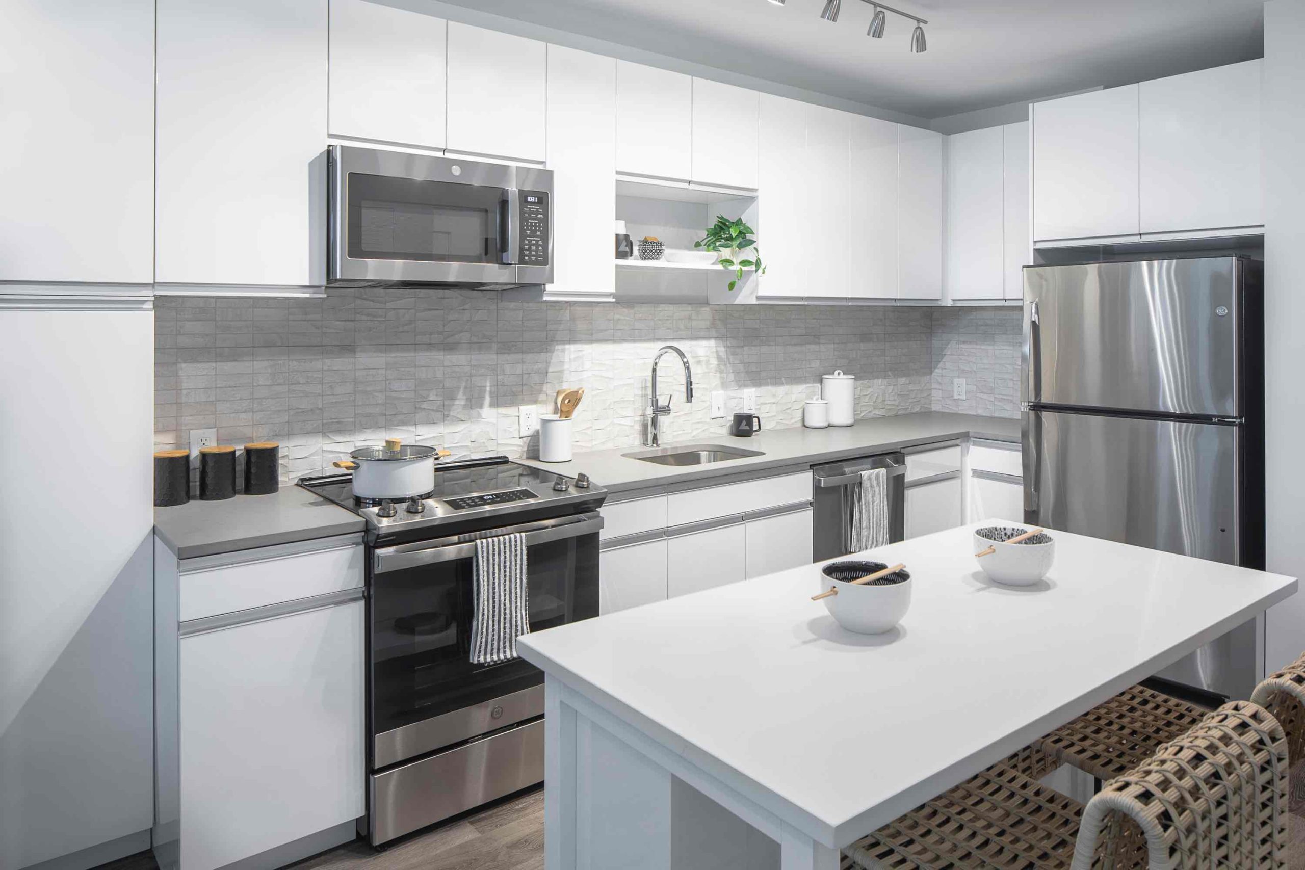 Contemporary kitchen with white counter top & stainless steel appliances. Inside our luxury apartments at 250 Mission.