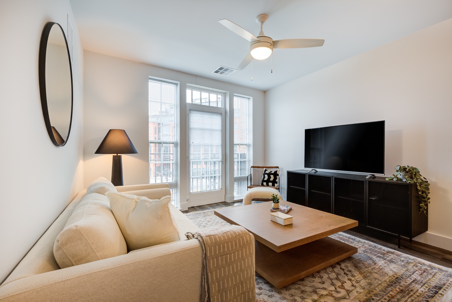 Relaxing living room setup with couch, television, and fan, plus balcony. Inside our luxury apartments at 250 Mission.