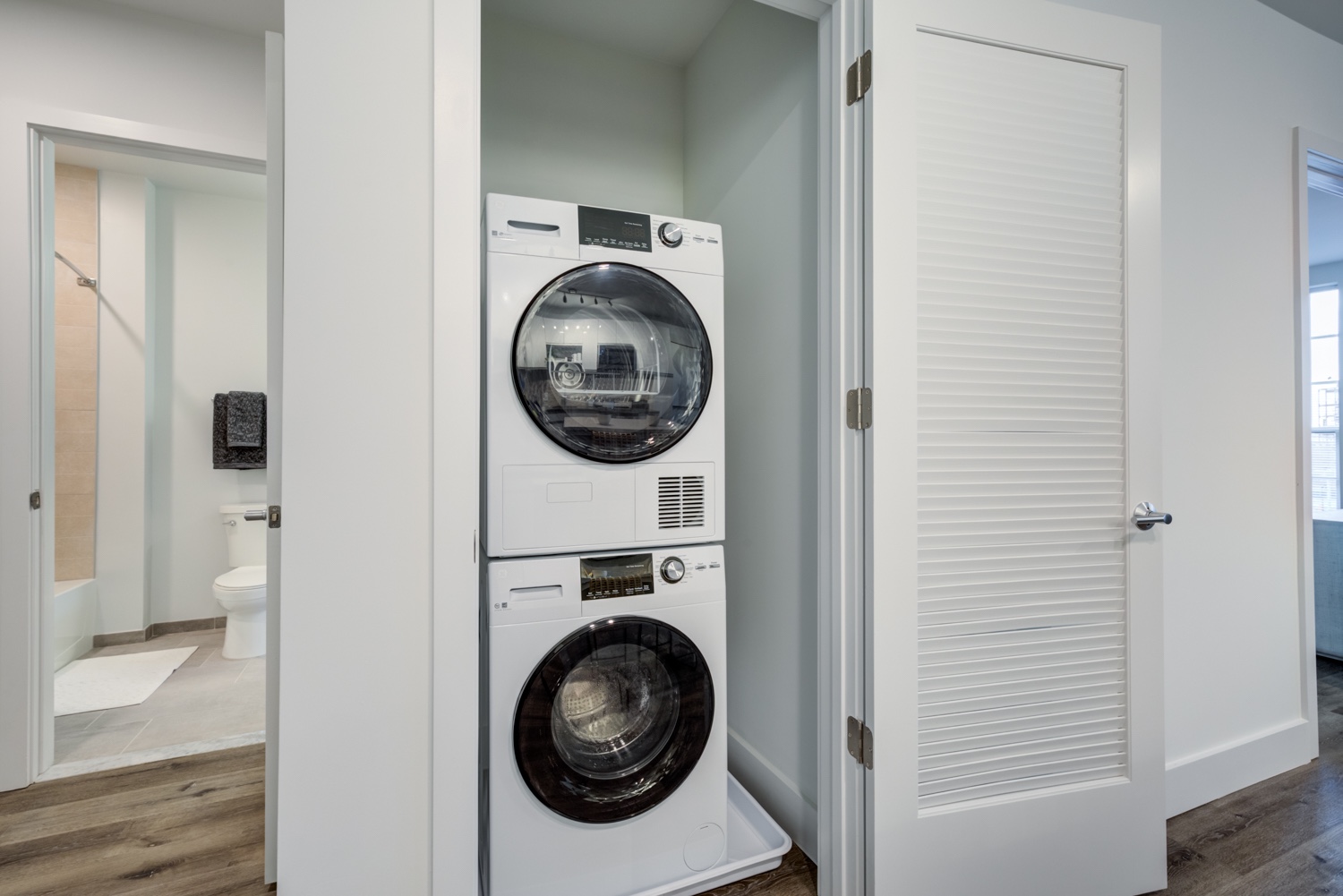 Washer and dryer with open toilet and bedroom door at the background. Inside our luxury apartments at 250 Mission.